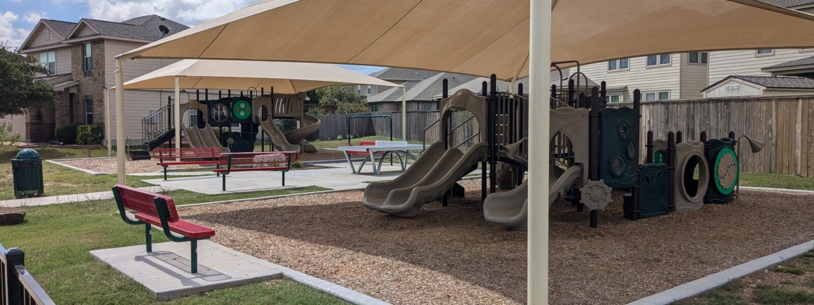 Playgrounds under shade structures, with park benches nearby.